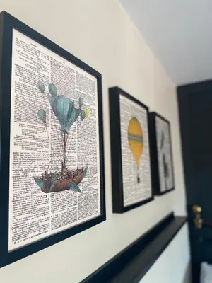 a wall with three framed pictures and a picture of a balloon at T'house in wigan in Pemberton