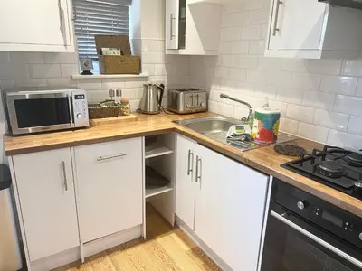a kitchen with white cabinets and a sink and a microwave at The Wilsons Courtyard, 2 - Bed, Sleeps 4, Pets Welcome in Ulverston