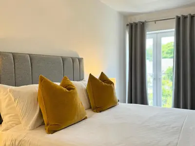 a bedroom with a bed with yellow pillows and a window at The Wilsons Courtyard, 2 - Bed, Sleeps 4, Pets Welcome in Ulverston