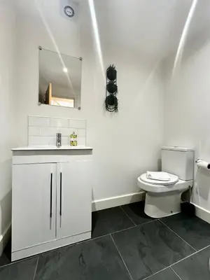 a white bathroom with a toilet and a mirror at The Wilsons Courtyard, 2 - Bed, Sleeps 4, Pets Welcome in Ulverston