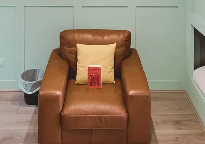 a brown leather chair with a yellow pillow on it at Pitchside Rooms Near Anfield in Liverpool