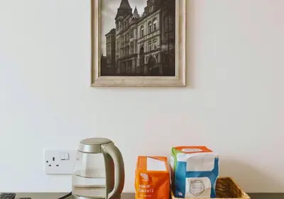 a table with a coffee pot and a picture on the wall at Pitchside Rooms Near Anfield in Liverpool