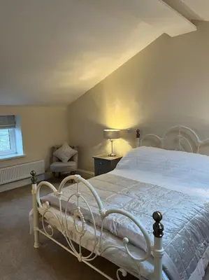 a bedroom with a white bed and a chair at Converted Barn with Hot Tub, The Hayloft. in Carnforth
