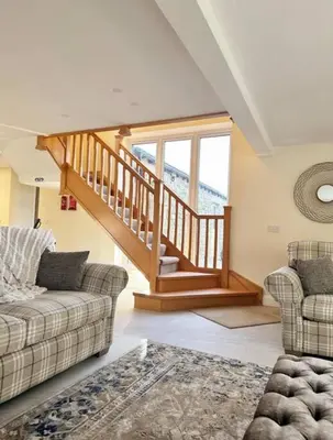 a living room with two couches and a staircase at Converted Barn with Hot Tub, The Hayloft. in Carnforth