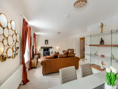 a living room with a brown couch and chairs at Cartmel Place in Cartmel