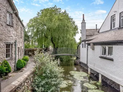 a bridge over a river between two buildings at Cartmel Place in Cartmel