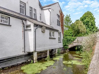 a river with algae in the water next to buildings at Cartmel Place in Cartmel