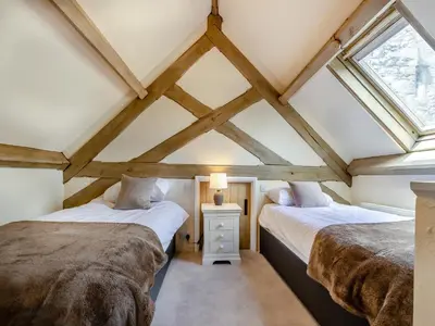 two beds in a room with two windows at Cartmel Place in Cartmel