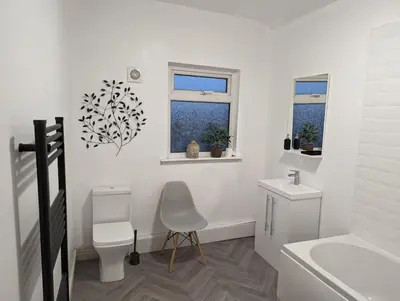 a white bathroom with a chair and a sink at The road to Wigan Pier in Pemberton