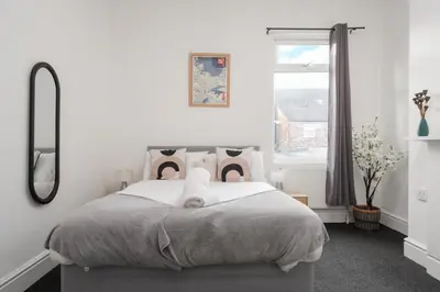 a white bedroom with a bed and a window at Anfield Abbey House in Liverpool