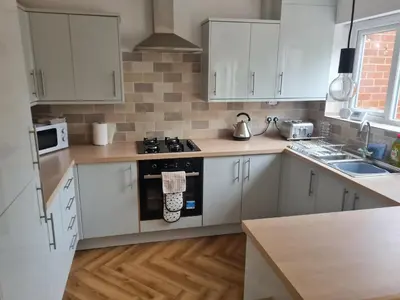 a kitchen with white cabinets and a stove top oven at 5Bed House Wirral near Liverpool Chester in Wirral