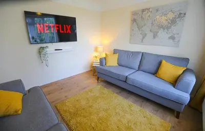 a living room with a blue couch and yellow pillows at 5Bed House Wirral near Liverpool Chester in Wirral