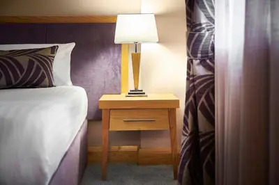 a bedroom with a bed and a lamp on a night stand at Best Western Premier Suites Hotel & Spa Liverpool-Knowsley in Knowsley