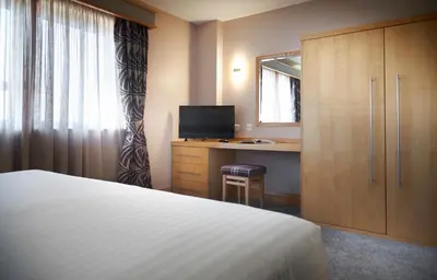 a bedroom with a bed and a desk with a mirror at Best Western Premier Suites Hotel & Spa Liverpool-Knowsley in Knowsley