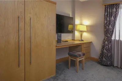 a hotel room with a desk and a tv at Best Western Premier Suites Hotel & Spa Liverpool-Knowsley in Knowsley