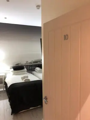a bedroom with a bed with white sheets and pillows at Happy Return Hotel in Blackpool