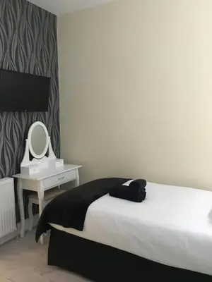 a bedroom with a bed and a desk with a mirror at Happy Return Hotel in Blackpool