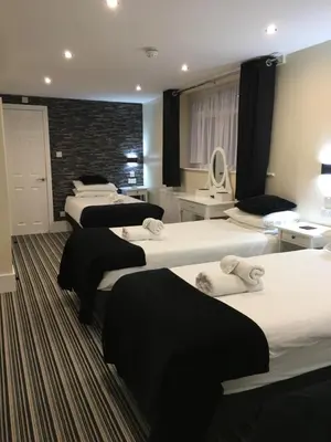 a hotel room with four beds and a brick wall at Happy Return Hotel in Blackpool