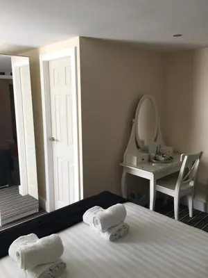 a bedroom with a bed and a dressing table and a mirror at Happy Return Hotel in Blackpool