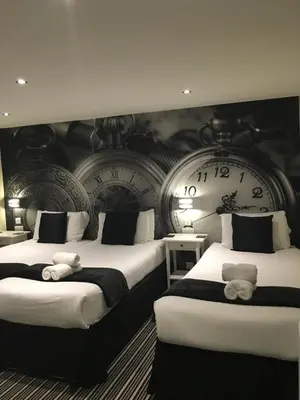 two beds in a room with clocks on the wall at Happy Return Hotel in Blackpool