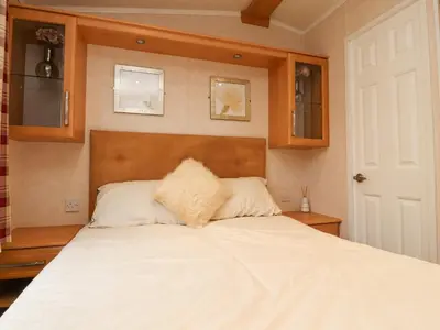 a bedroom with a white bed with a wooden headboard at Larenzo in Preston