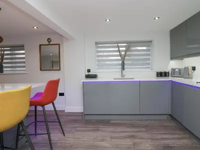 a kitchen with white cabinets and orange chairs at Crag View Cottage in Barrow in Furness