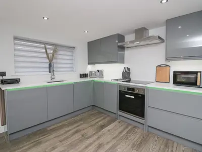 a kitchen with white cabinets and green counter tops at Crag View Cottage in Barrow in Furness