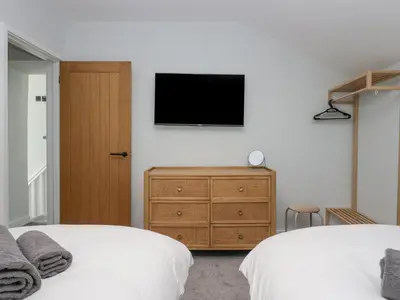a bedroom with two beds and a television on the wall at Crag View Cottage in Barrow in Furness