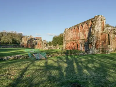 a ruin of a castle with a bench in the grass at Crag View Cottage in Barrow in Furness