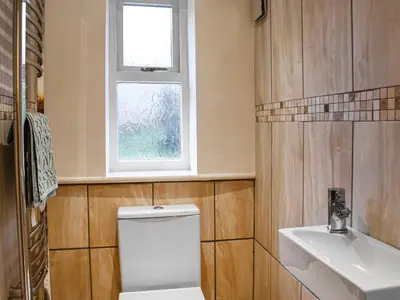 a bathroom with a toilet and a sink and a window at Beech Cottage in Carnforth