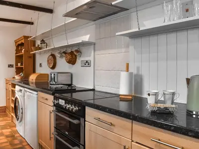 a kitchen with a black counter top and a dishwasher at Beech Cottage in Carnforth