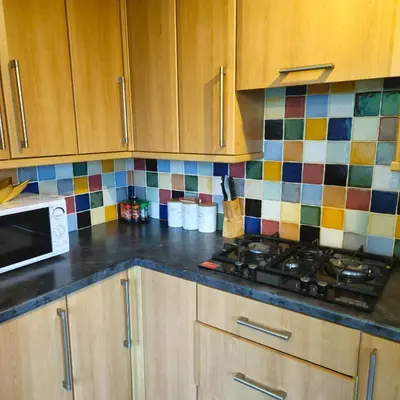 a kitchen with wooden cabinets and a stove top at Aldwych house, For Holidays, Contractors & Relocation, Free Parking & Wi-Fi in Preston
