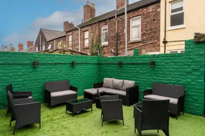 a patio with chairs and a green wall at Home at 42 Arkles Lane Anfield in Liverpool