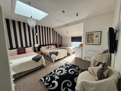 a bedroom with three beds and a couch and a room at The Holmlea in Blackpool