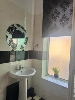 a bathroom with a sink and a mirror and a window at The Holmlea in Blackpool