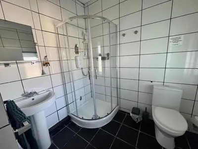 a bathroom with a shower and a toilet and a sink at The Holmlea in Blackpool