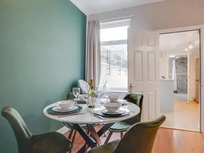 a dining room with a white table and green chairs at Ivy House, 3 Bed House, Parking - Pass the Keys in Liverpool