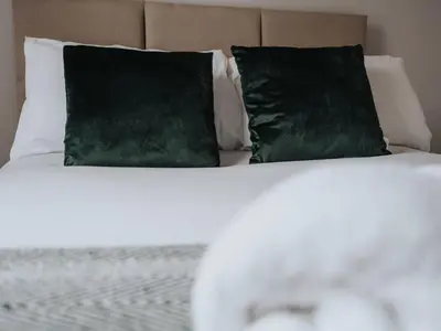 a bed with two green pillows on top of it at Ivy House, 3 Bed House, Parking - Pass the Keys in Liverpool