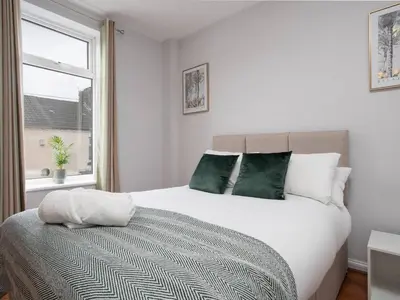 a bedroom with a large white bed with green pillows at Ivy House, 3 Bed House, Parking - Pass the Keys in Liverpool