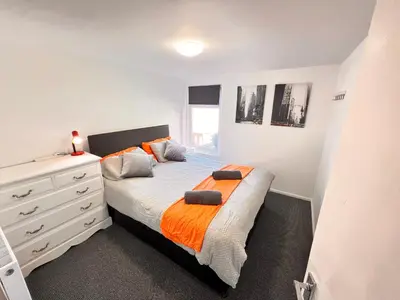 a bedroom with a bed with an orange blanket and a dresser at Manhattan loft Apartment by Wilom in Blackpool