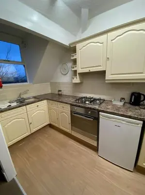 a kitchen with white cabinets and a sink and a stove at Garnett - Comfy apartment, great location! in Clitheroe