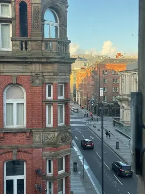 a view of a city street with a building and cars at City Centre Apartment Liverpool in Liverpool