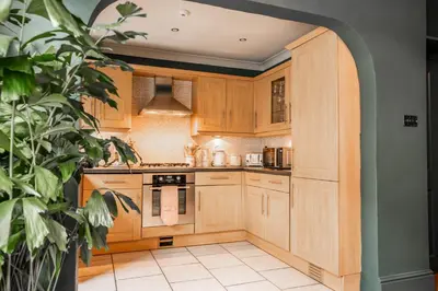 a kitchen with wooden cabinets and a potted plant at Arkles - Victorian Gem in Liverpool