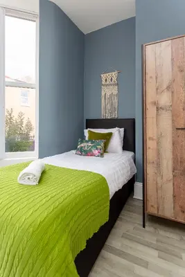 a bedroom with a bed with a green blanket at Edge Grove Retreat - Air Host & Stay in Liverpool