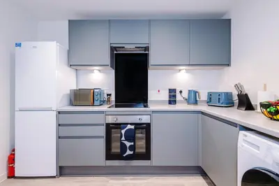 a kitchen with white appliances and blue cabinets at NEW! Pristine 2-Bed Flat on Liverpool by 53 Degrees Property, Amazing Location, Sleeps 6! in Liverpool