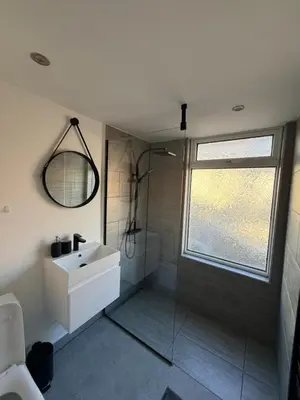 a bathroom with a sink and a shower and a mirror at Cityscape-Cosy House By Anfield in Liverpool