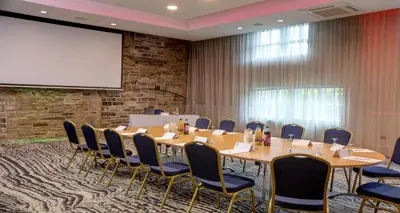 a conference room with a table and chairs and a projection screen at Best Western Plus Lancashire Manor Hotel in Skelmersdale
