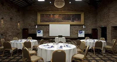 a conference room with tables and chairs and a screen at Best Western Plus Lancashire Manor Hotel in Skelmersdale