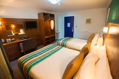 a hotel room with two beds and a television at Best Western Plus Lancashire Manor Hotel in Skelmersdale