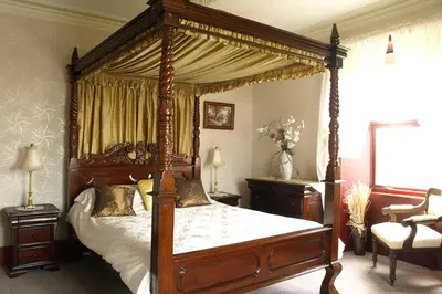 a bedroom with a canopy bed and a chair at Duddon Villa in Millom